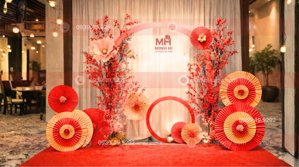 Decor tết 2026 cho văn phòng với background cánh quạt xoà đỏ cùng hoa nụ tầm xuân