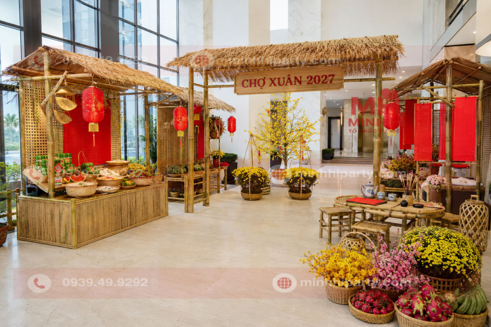 Không gian chợ xuân trang trí Tết cho chung cư 2027 với gian tre mái lá, bàn trà, thư pháp và lối đi rộng.