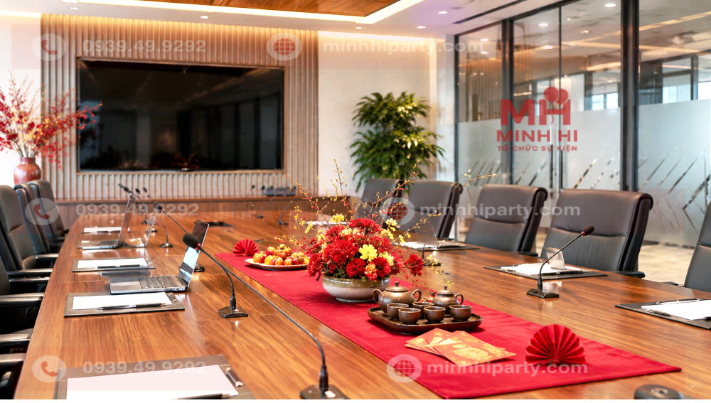 Trang trí phòng họp đón Tết 2027 bằng cây mai vàng, bình hoa đào, bao lì xì và đồng tiền vàng sang trọng.
