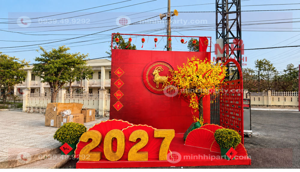 trang tri tet cho san khau truong hoc 2027 Mẫu trang trí Tết 2027 cho trường học với sân khấu hội xuân Đinh Mùi, hoa mai, quạt đỏ và bộ số 2027.