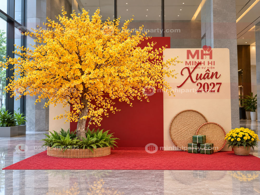 Cây mai giả trang trí tiểu cảnh Tết 2027 phối backdrop Xuân 2027, mẹt tre, bánh chưng mô hình và chậu cúc vàng tại sảnh lớn.
