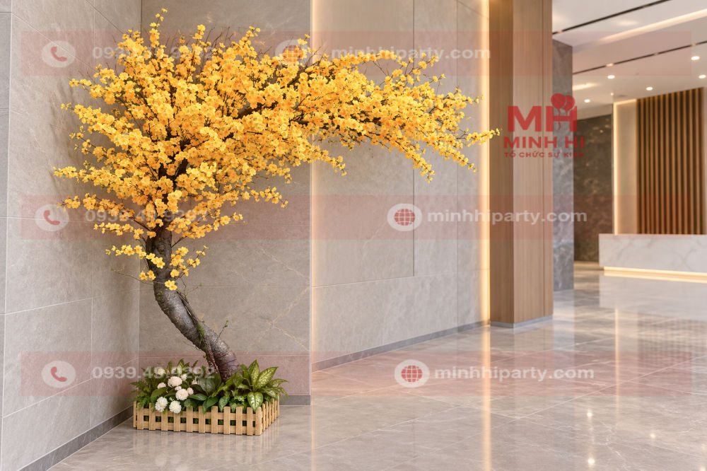 Cây mai giả trang trí tết 2027 dáng nghiêng, tán lệch hoa vàng đặt tại góc sảnh, phần gốc trang trí hàng rào tre và hoa nhỏ.