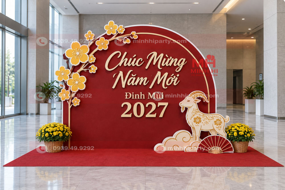 Trang trí Tết văn phòng 2027 với backdrop vòm đỏ trầm, chữ nổi kem và hoa mai formex.
