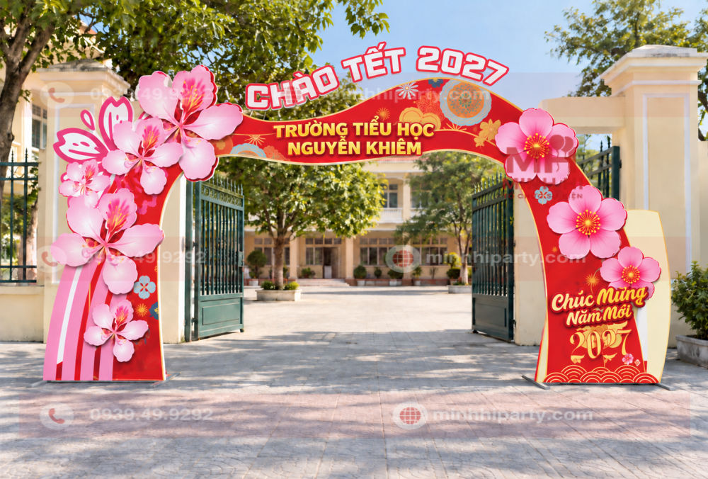 Trang trí cổng chào tết 2027 với hoa đào hồng bên phải và nền sân không trải thảm.