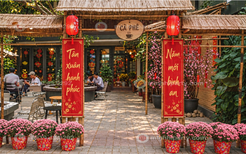 Câu đối Tết cổ truyền màu đỏ treo hai bên cổng tre quán cafe, kết hợp lồng đèn và hoa cúc vàng.