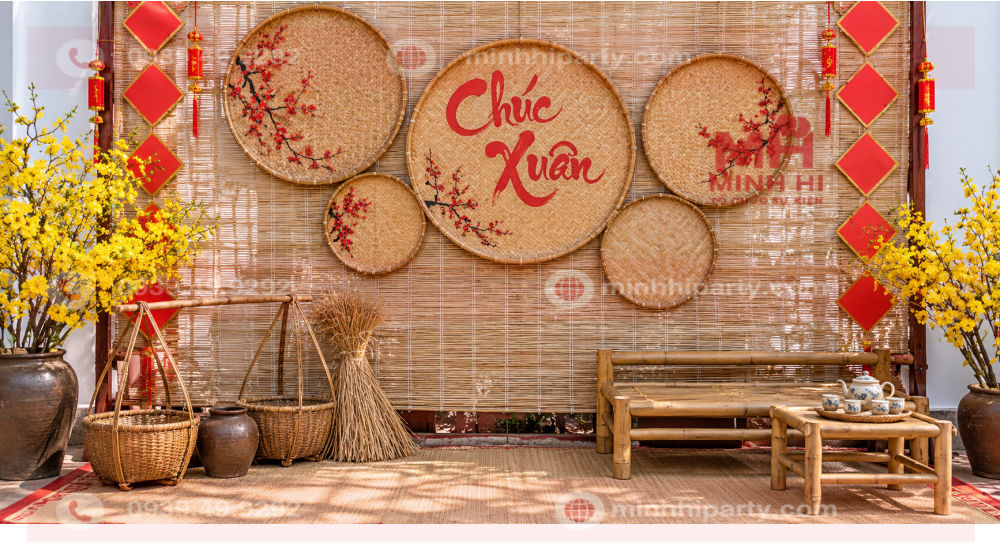 Mẹt tre trang trí Tết 2027 trên mành nền, kết hợp quang gánh, chum đất và bàn ghế tre.