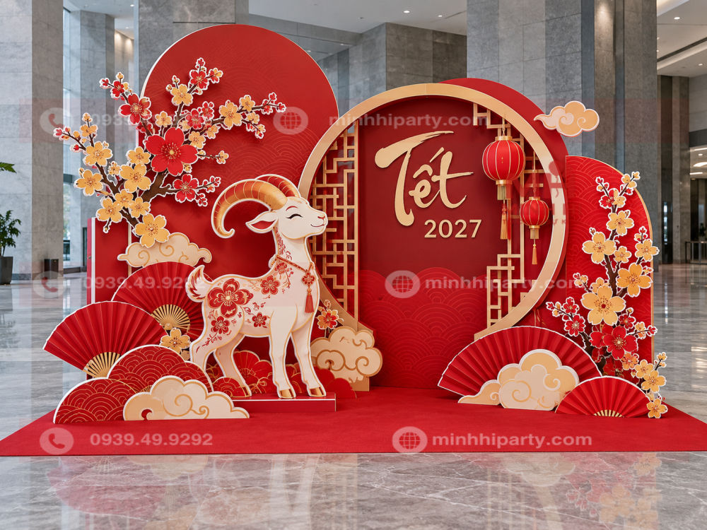 Tiểu cảnh Tết Đinh Mùi 2027 với linh vật dê Fomex cách điệu, hoa mai vàng đỏ viền trắng, quạt giấy và backdrop hình tròn.